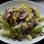 Mushroom Caesar Salad with chopped romaine and sliced marinated mushrooms in a bowl.