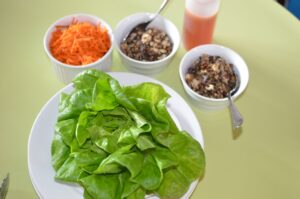 Dishes of grated carrot, tofu vegetable filling, sauce and lettuce leaves.