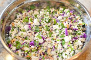 Hand chopped tofu, herbs and vegetables in a bowl.