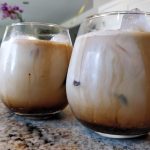 Iced coffees in a glass on the counter.