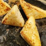 Frying triangles of feta in a skillet until golden brown.