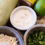 Elote ingredients: greek yoghurt mayonnaise mixture, ears of corn, queso fresco, cilantro, spices and lime.