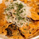 Pumpkin ravioli with mushrooms garnished with parmesan and rosemary