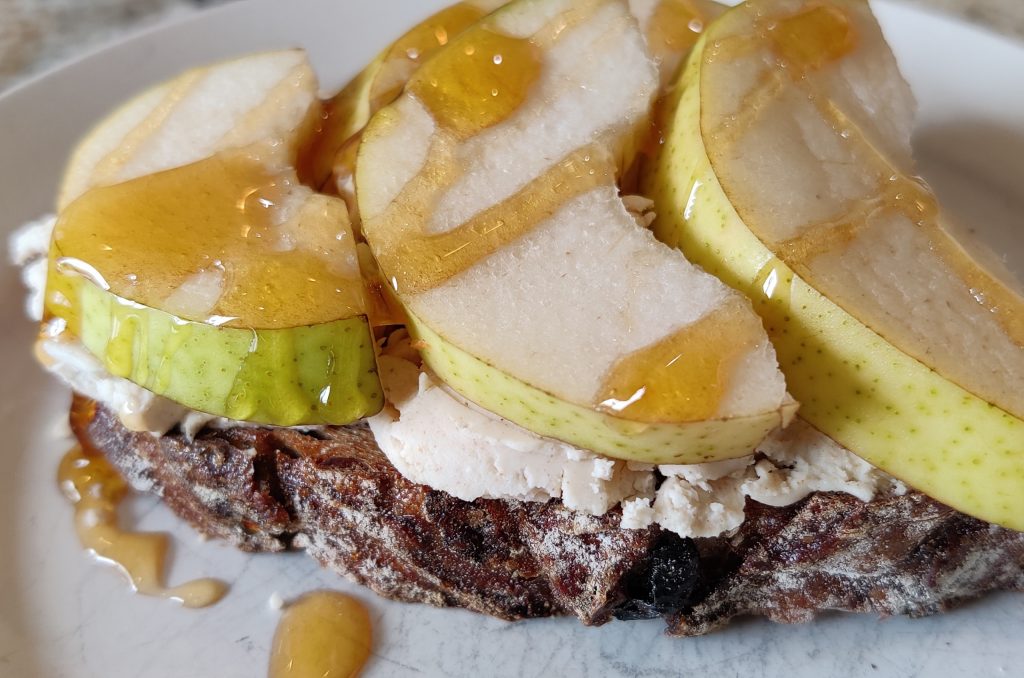 Sliced sourdough bread toasted, spread with a creamy goat cheese, topped with sliced pears and honey.