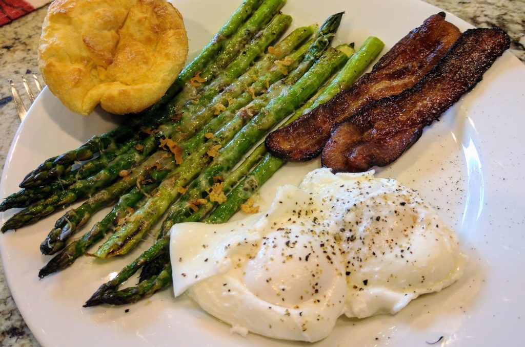 Roasted asparagus, poached eggs, bacon and popovers on a plate