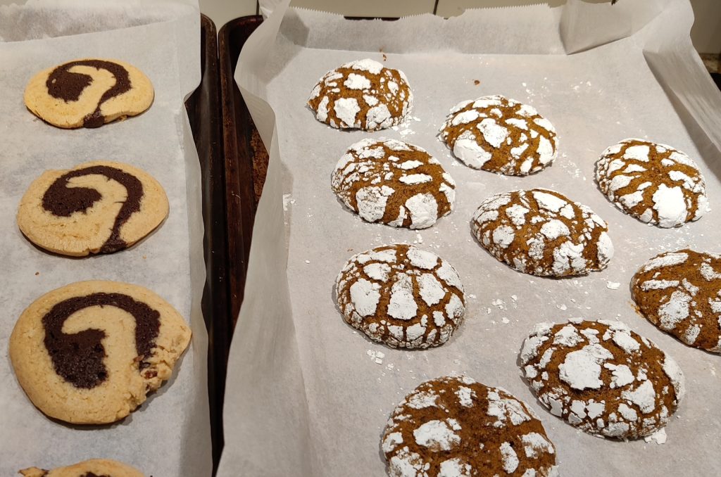 Baking sheets lined with parchment paper and two batches of freshly baked cookies