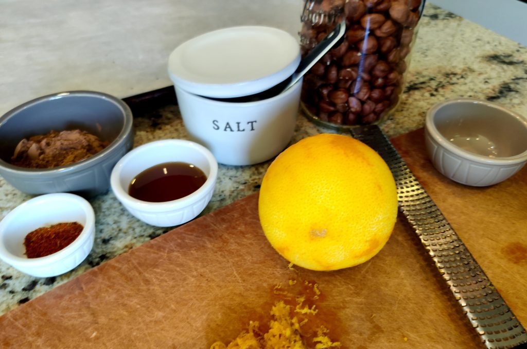 Kitchen counter layout of small bowls and jars of ingredients next to a cutting board, lemon zester and parchment lined baking sheet.