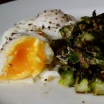 Poached egg with roasted asparagus on a serving plate.