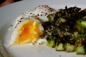Poached egg with roasted asparagus on a serving plate.