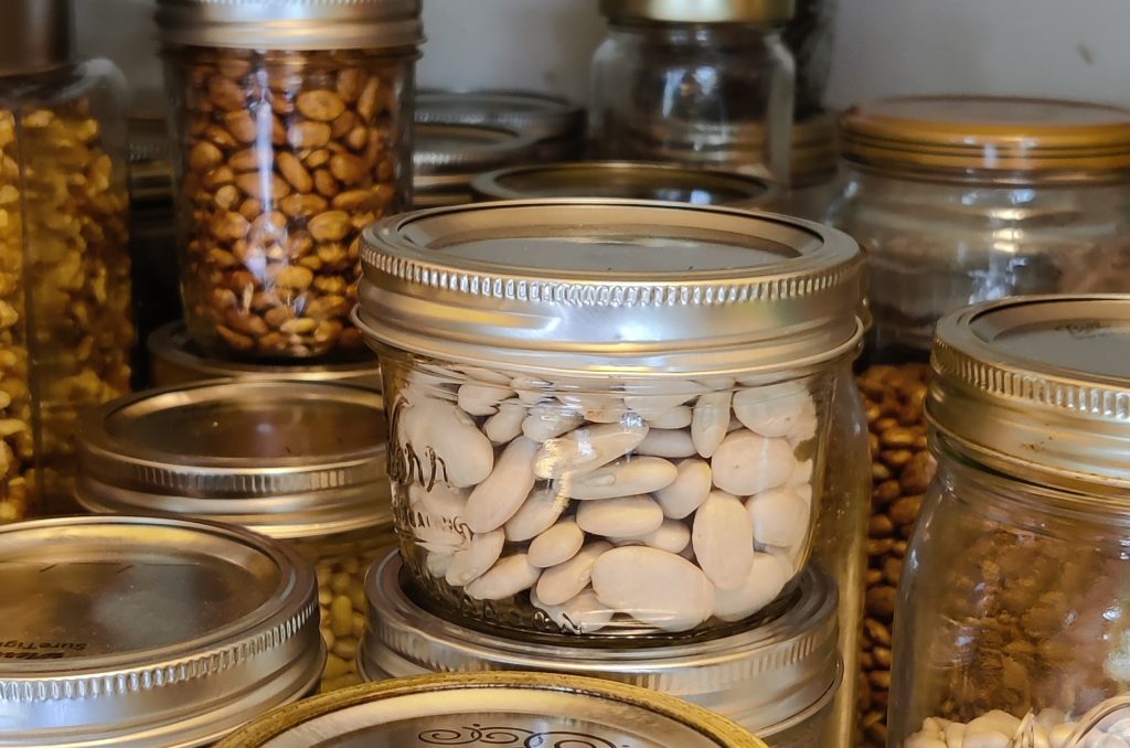 Bulk grocery items like beans stored in glass canning jars in the pantry.
