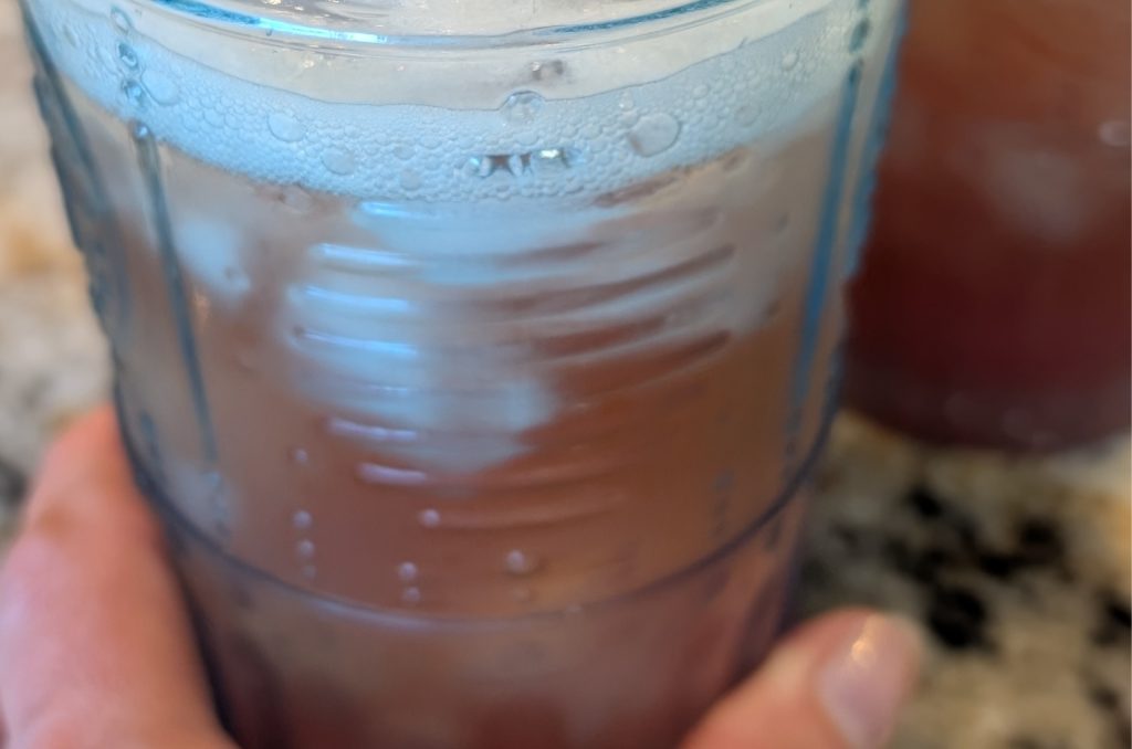 Homemade strawberry rhubarb shrub in a glass with ice