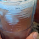 Homemade strawberry rhubarb shrub in a glass with ice
