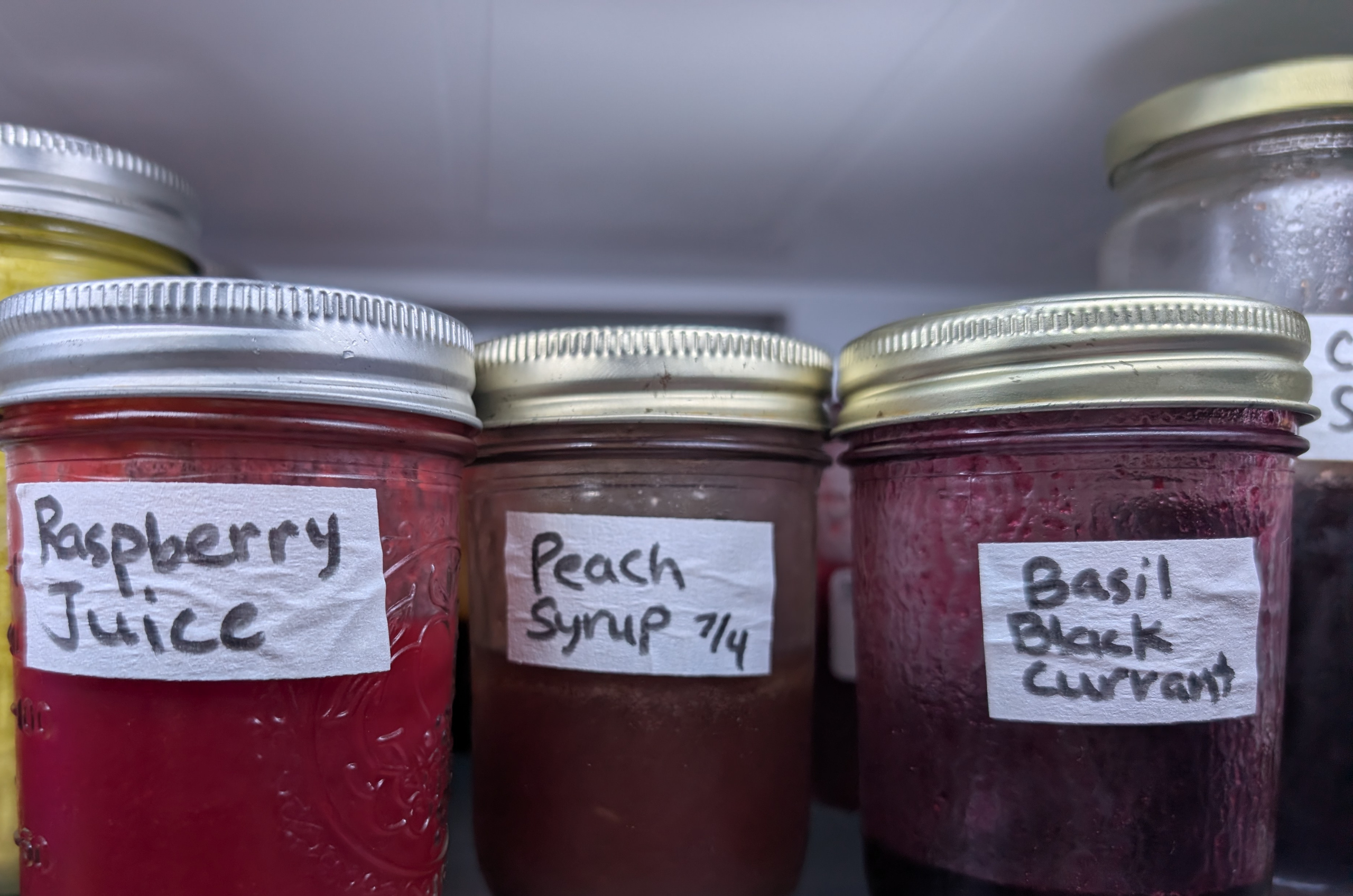 Fruit syrups and juices in jars in the fridge.
